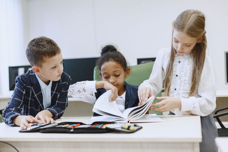 Three children engaged in a group project in a modern classroom setting.